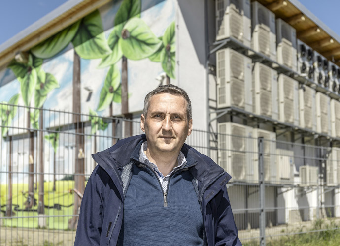 Michael Knape, Bürgermeister, vor Batteriespeicher. Energieautarkes Dorf Feldheim. Deutschland 2025